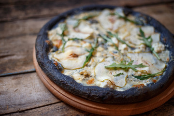 Black quattro formaggi pizza on wooden background