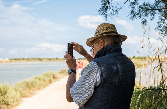 Italy, Sicily, Vendicari nature reserve, senior man taking a smartphone picture