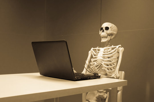 esqueleto en oficina trabajando y muerto de aburrimiento