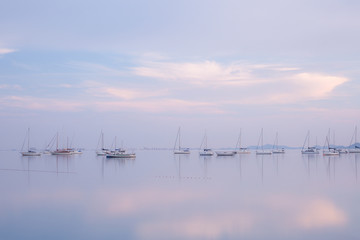 Fototapeta na wymiar view of boats reflected over the calm sea at blue hour