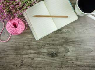 Flat lay,top view grey wooden desk with stationery including notebook and pencil with a cup of coffee,flowers  and copy space 