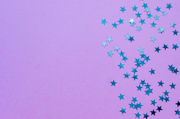 Holographic stars on trendy purple background. Festive backdrop. Top view. Copy space.