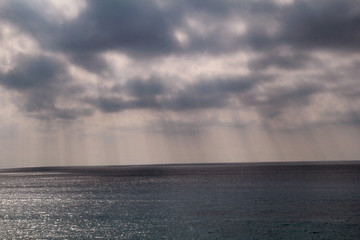 Obraz premium Dramatic sunset skies with grey clouds with lines of sun to tropical mediterranean sea. Beautiful natural environment. Panorama landscape and horizon of sun beams over calm ocean, amazing view scene.