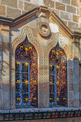 Fototapeta premium Close-up view of an ancient window with ornate decorated metal bars in an old limestone fortification wall.