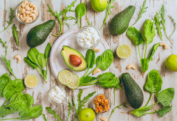 Avocado, lime, spinach, ricotta cheese, walnut and cashew nuts, arugula salad on a white shabby background. top view