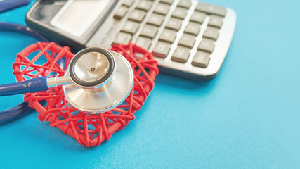 red heart and calculator with stethoscope isolated on blue background. tax offset concept. Medical...