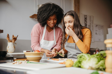 Teacher assisting student smelling cut vegetable in cooking class