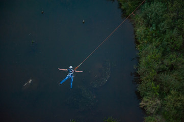 Extreme jump from the bridge. The man jumps surprisingly quickly in bungee jumping at Sky Park explores extreme fun. Bungee in the canyon.