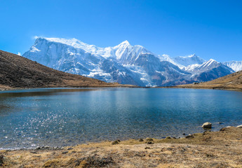 Ice lake, as part of the Annapurna Circuit Trek detour, Himalayas, Nepal. Annapurna chain in the back, covered with snow. Clear weather, dry grass, snowy peaks. Freedom, solitude, chill and relaxation