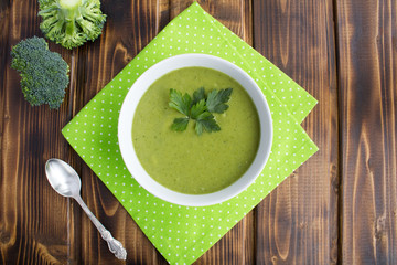 Vegetarian  broccoli puree soup in th white bowl on the brown  wooden background.Top view.