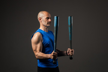 Athletic, middle aged man training with clubbells, studio background