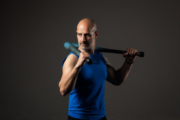 Athletic, middle aged man training with clubbells, studio background