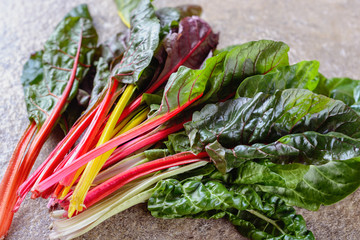 A lot of leaves of chard as a kind of a beet of a variety with broad colorful leaf stalks that may be prepared and eaten separately from the green parts of the leaves
