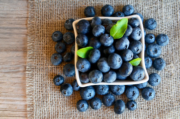 Freshly picked organic blueberries in a white bowl on a burlap cloth background. Blueberry.Bilberries.Healthy eating,vegan food or diet concept with copy space.Selective focus.