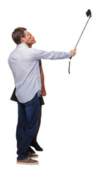 Back view of an interracial couple that makes selfie on selfie stick.