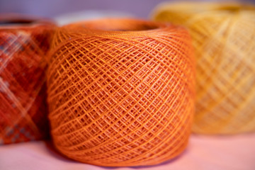 Balls of colored threads of beige tones on a colorful neon background