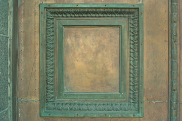 Image of a fragment of a wooden door with a bronze ornament