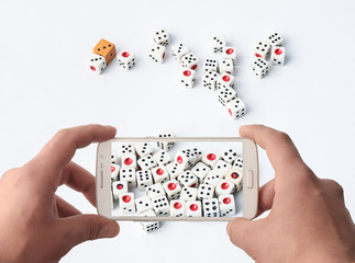 Fototapeta na wymiar Mobile phone and dice chips on a white gaming table
