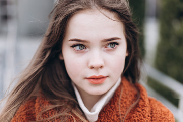 Obraz premium Outdoor urban portrait of cheerful beautiful caucasin young girl in coat. Casual style concept