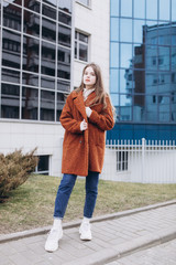 Outdoor urban portrait of cheerful beautiful caucasin young girl in coat. Casual style concept