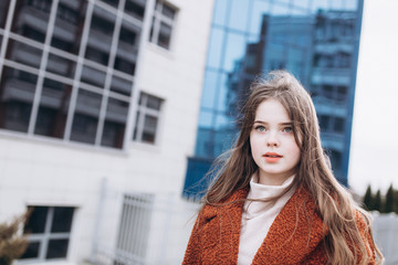 Outdoor urban portrait of cheerful beautiful caucasin young girl in coat. Casual style concept