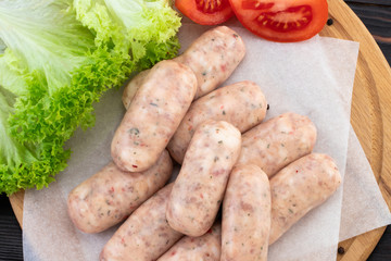 Fresh raw sausage on the wooden background, top view