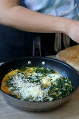 Unrecognizable person making frittata with chicory and cheese. Selective focus.
