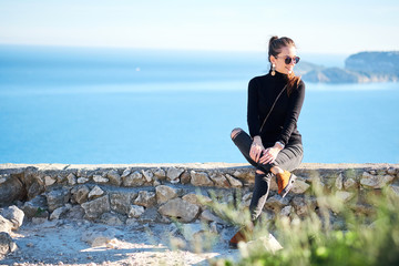Young woman is enjoying nature with panoramic sea view from a cliff.