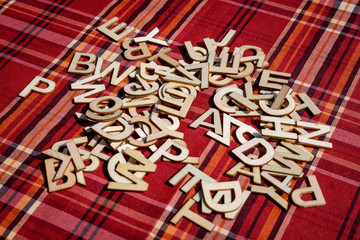Group of mixed wooden letters on red textile material with colored stripes, top view, flat lay