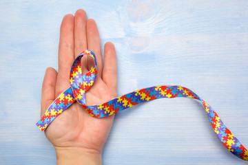 World Autism awareness and pride day with Puzzle pattern ribbon on hand