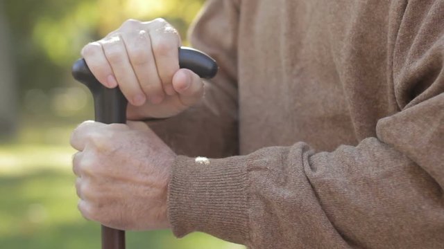 Closeup of senior man's hands leaning on cane. Bad feelings, Alzheimer symptoms