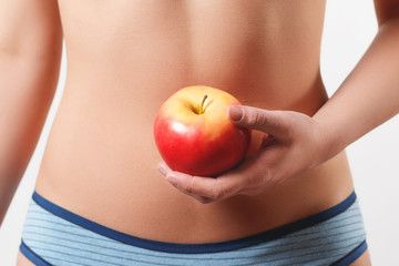 close up. slender slim figure waist belly young woman girl. Holding a juicy red Apple. isolated on white background