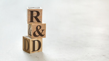 Pile with three wooden cubes - letters R&D meaning Research and Development on them, space for more...