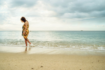 beautiful young girl in pareo walking on the sunset beach on sunlight in Philippines - Summer vacation background