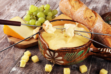 Gourmet Swiss fondue dinner on a winter evening with assorted cheeses on a board alongside a heated...