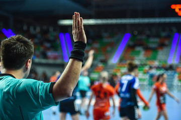 Handball referee gives signal playing for time during handball match.