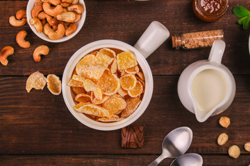 cornflakes, coffee, cottage cheese, bread, butter, eggs, jam and other ingredients for breakfast on a dark background. Top view with copy space