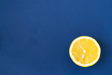 Fresh lemon slice close up on bright blue background. Flat lay.
