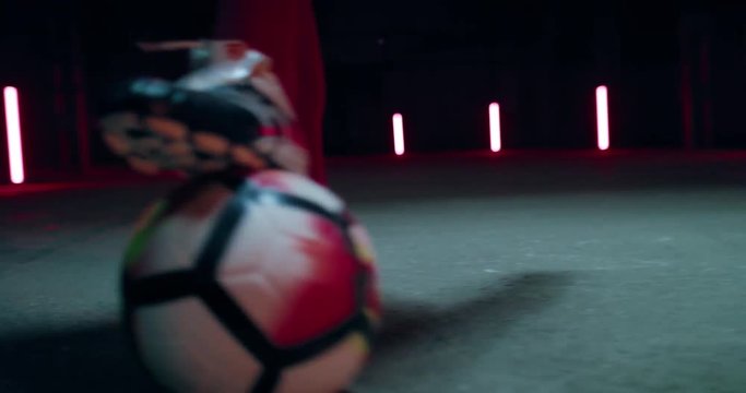 HANDHELD Caucasian professional football soccer player practices dribble and tackle in a large abandoned warehouse. 4K UHD 60 FPS SLOW MOTION