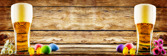 Glass of cold light beer with Easter decorations on a wood background for the Easter holidays