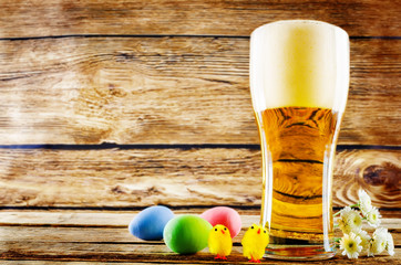 Glass of cold light beer with Easter decorations on a wood background for the Easter holidays