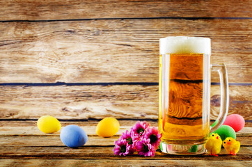 Glass of cold light beer with Easter decorations on a wood background for the Easter holidays