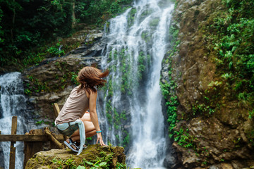 Young woman enjoying natural bathing by the Tamaraw waterfall on background.