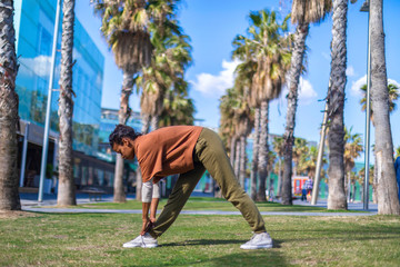 Black woman, afro hairstyle, doing yoga asana under the palms in a promenade