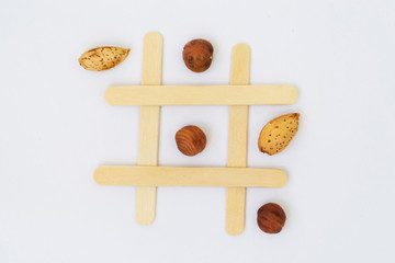 Pistachio nuts and dried fruits on the field for the game of tic-tac-toe on a white background