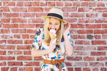 Girl with fedora hat bites into an ice cream cone in the summer and feels pain due to tooth...