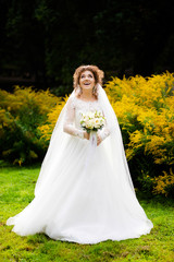 The charming bride in a white dress with lace poses in the park