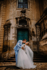 Naklejka premium Young beautiful couple bride and groom kisses each others on the background of the church