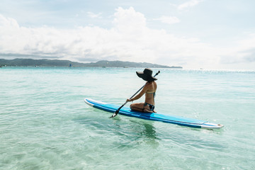 Woman is enjoying a view in standup paddleboarding over the ocean