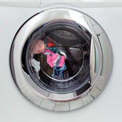Round transparent door hatch automatic washing machine, through which you can see the washing of colored linen.